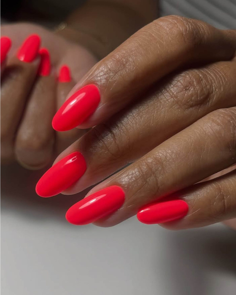 Smooth and glossy roundtip coral red neon nails.